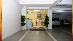 Un vestíbul net i modern, amb una escala que puja a plantes superiors, plantes en testos i un aparcament al fons.
