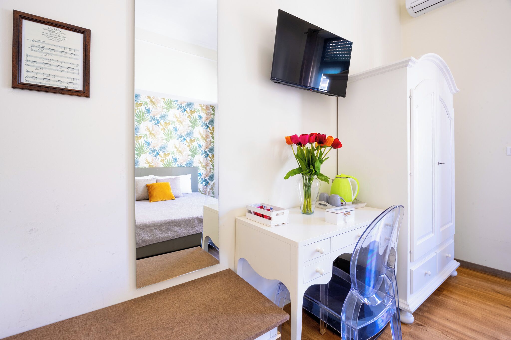 A bedroom with a bed, a desk, a chair, a TV, and a wardrobe.