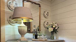 A vintage-style vanity with a mirror, a lamp, and a vase with flowers.