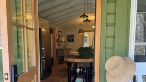 A wooden door with glass panels leading into a room with a kitchen, a dining table, and a hanging light fixture.