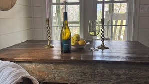 A rustic dining table with a bottle of wine, glasses, and lemons.