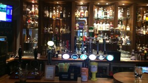 A bar area with a variety of liquor bottles, a sign reading "Welcome to the Eagle Hotel," and a bar counter with multiple taps and glasses.