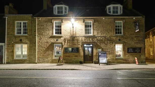A stone building with a sign reading "The Eagle Hotel" at night.