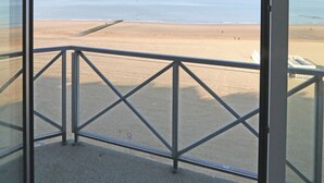 Ein Balkon mit Metallgeländer, der Blick auf einen Strand bietet.