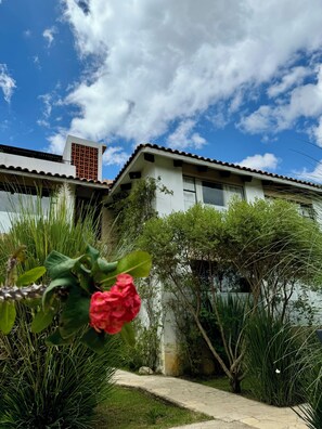 A building with a tiled roof, surrounded by greenery and a clear sky.
