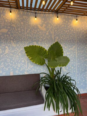 Ein Zimmer mit Wandgestaltung, einem braunen Sofa und einer großen Grünpflanze.