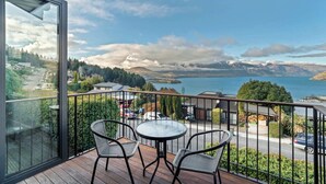 A balcony with two wicker chairs and a small round table, overlooking a scenic view of a lake and mountains. - Elevated Elegance in Fernhill (Queenstown)