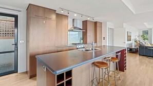 A modern kitchen with a large island, stainless steel appliances, and bar stools. - Elevated Elegance in Fernhill (Queenstown)