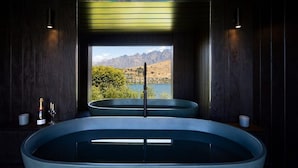 A spa area with a large bathtub and a smaller tub, both with a view of mountains and a lake.
