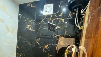 A bathroom with a black marble wall, a white toilet, a bidet, a shower, and a mirror.