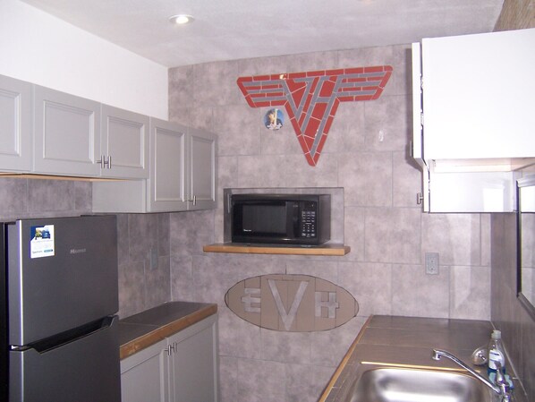 A kitchen with a refrigerator, microwave, and sink.