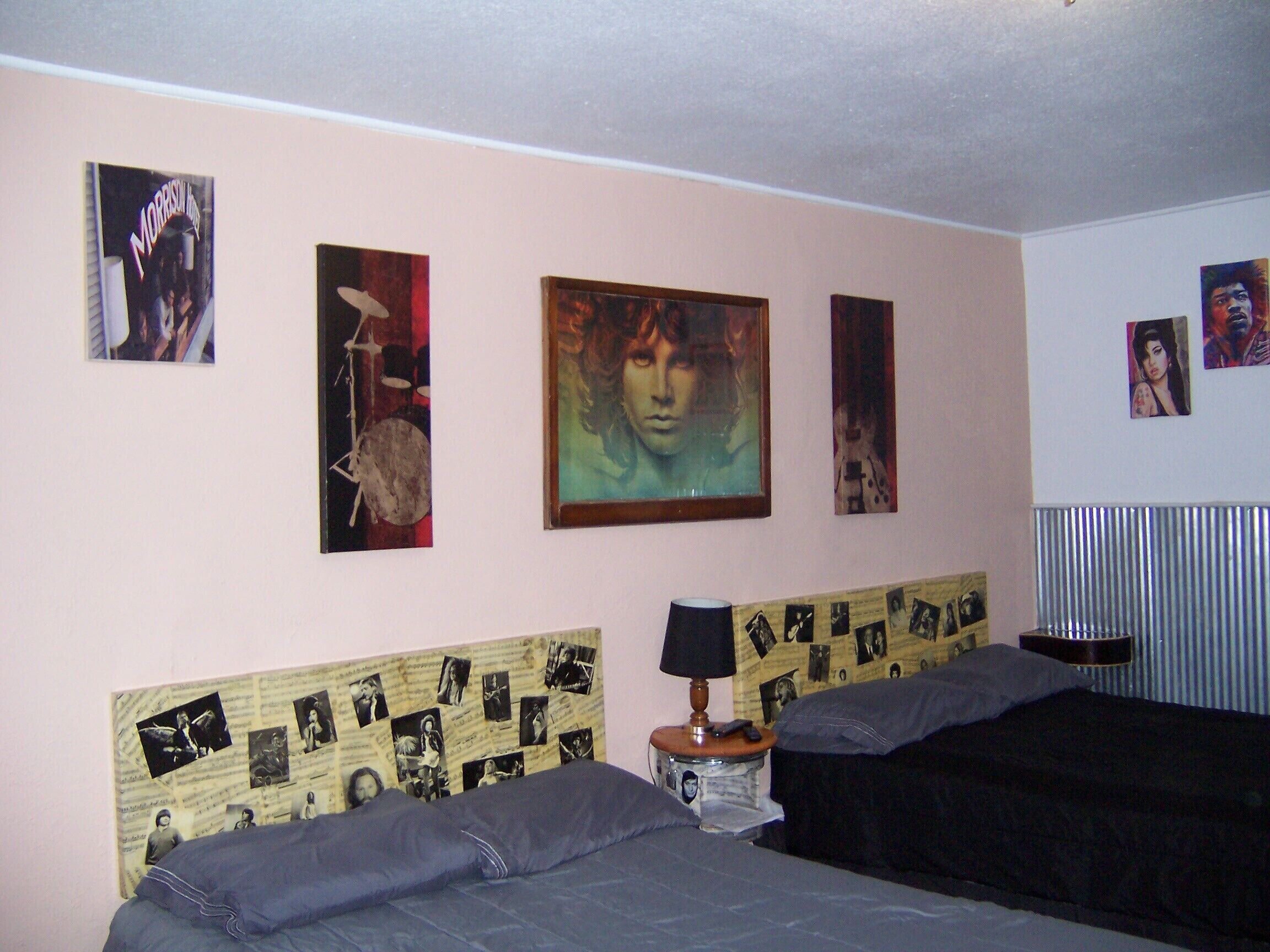 A bedroom with two beds, a headboard with photos, and various wall art.
