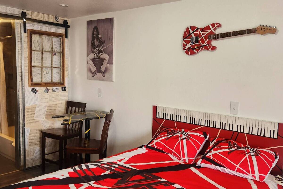 Une chambre à coucher avec un lit, une guitare, un piano et une petite table.
