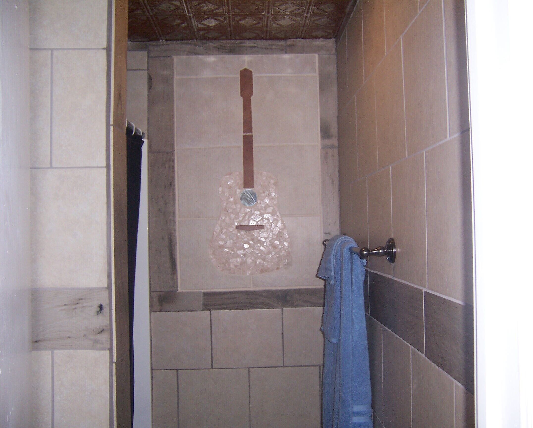 Un baño con ducha, paredes de azulejos y un toallero.