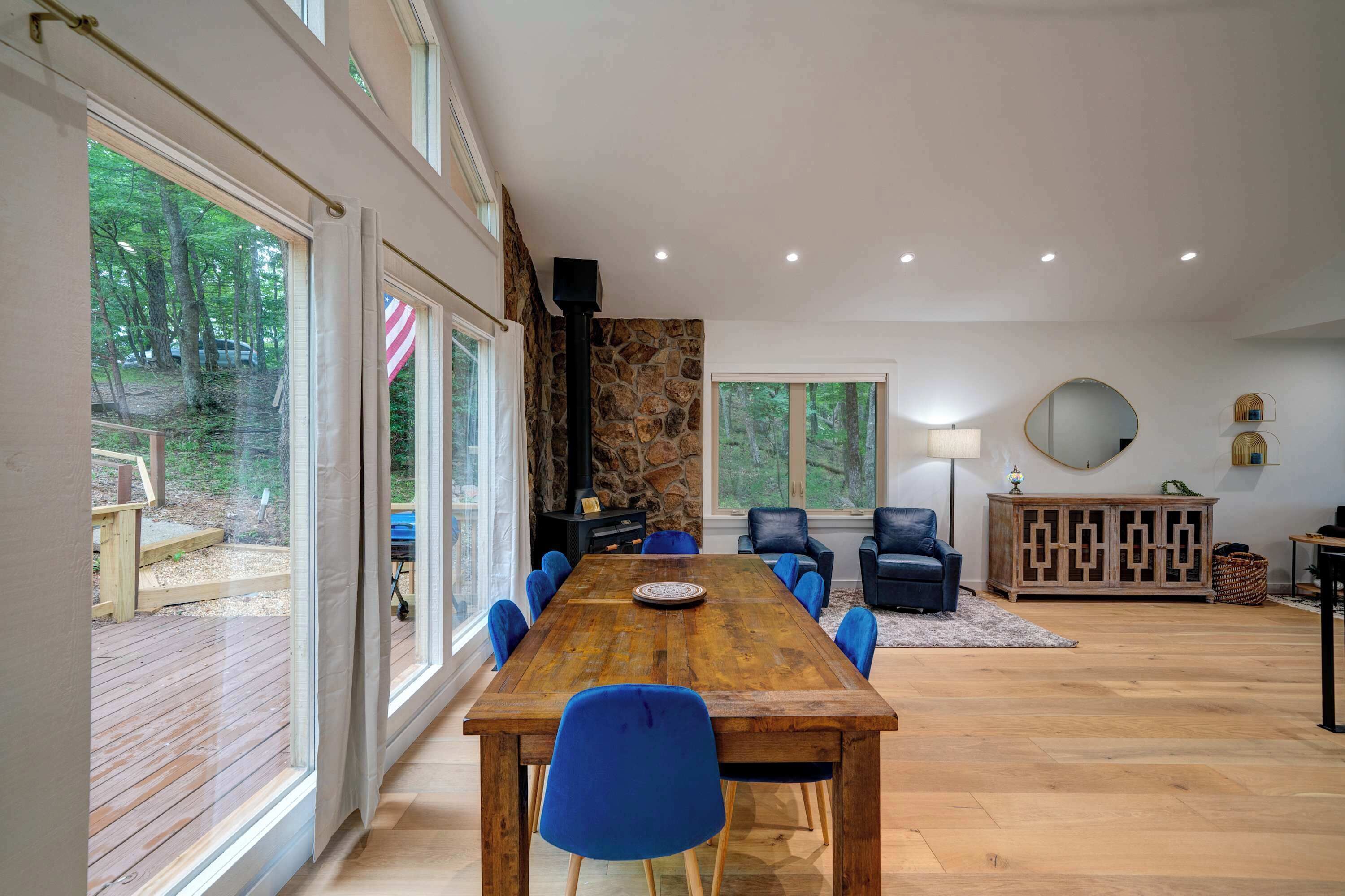A spacious dining area with a wooden table and blue chairs, a stone wall, and a view of the outdoors.