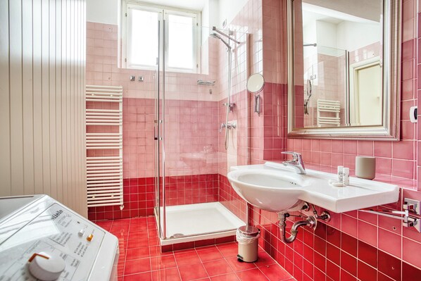 A bathroom with a glass shower enclosure, a white sink, and a mirror. - JOIVY Bright Flat near Parco Sempione (Milan)