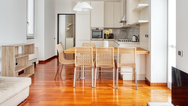 Une cuisine moderne avec un coin repas, un plancher en bois et une grande fenêtre.