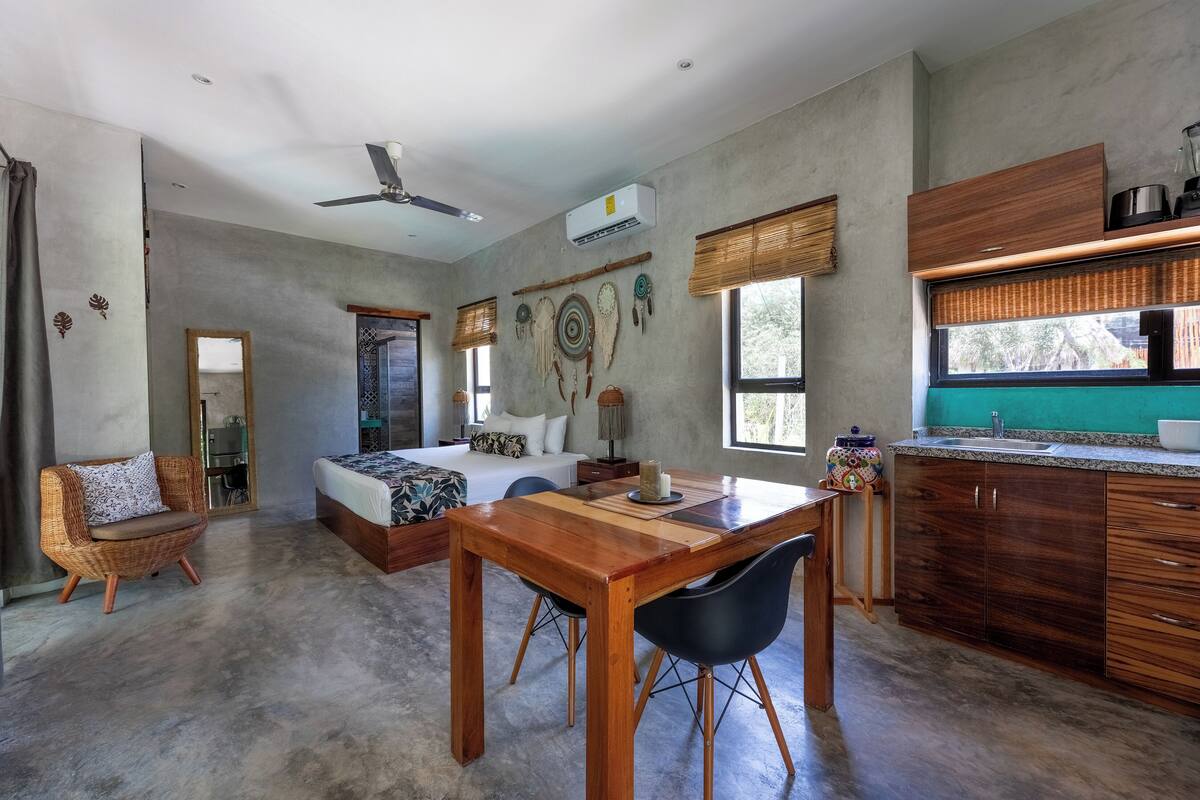 A modern room with a bed, a dining table, and a kitchen area.