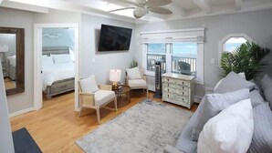 A bedroom with a bed, a desk, a chair, a dresser, a TV, and a view of the ocean. - Ocean front Scituate Minot Beach Front Sleeps 11 (Scituate)
