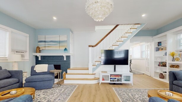 Una sala de estar moderna con una escalera, un televisor de pantalla plana y una chimenea.