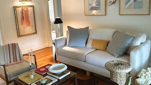 Ein Wohnzimmer mit einer Couch, Sesseln, einem Couchtisch und einem Bücherregal.