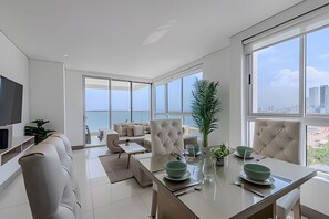 Ein modernes Wohnzimmer mit Essbereich, großen Fenstern und Meerblick.