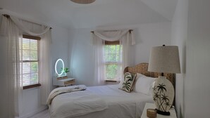 Un dormitorio con cama, mesita de noche, lámpara y espejo con luces.
