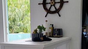 Una cocina con encimera blanca, decoración de timón de barco y ventana con vistas a zonas verdes.