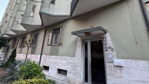 A multi-story building with a unique architectural design, featuring a curved facade and a small entrance with a glass door.
