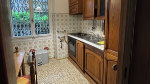 A kitchen with wooden cabinets, a gas stove, and a window with a view of greenery.