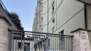 A gated entrance to a building with a stone facade and numbered doors.