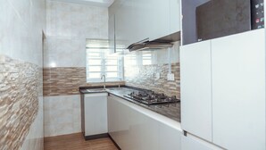 Una cucina moderna con mobili bianchi, piano cottura a gas e schienale in pietra.