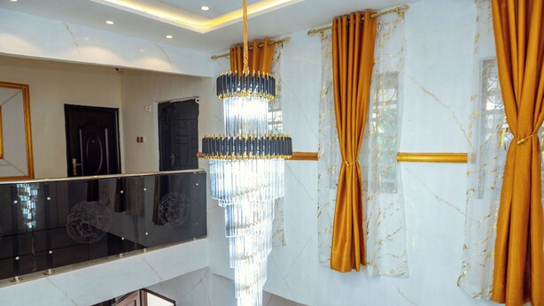 Un interno moderno con una parete in marmo, un lampadario e un balcone con ringhiera in vetro.