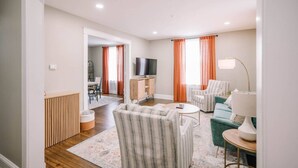 A modern living room with a sofa, armchairs, a TV, and a dining area. - Victorian Modern 3bd/2bath - Meredith’s Place (Danville)