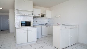 A modern kitchen with white cabinetry, a microwave, a dishwasher, and a sink. - Apartment in Agde With Direct Beach Access (Agde)