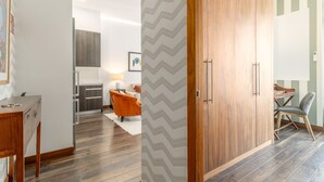 Ein modernes Wohnzimmer mit einem Holzschrank, einem Essbereich mit Tisch und Stühlen sowie einer Küche im Hintergrund.