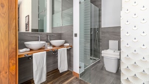 Ein modernes Badezimmer mit zwei großen weißen Waschbecken, einer Duschkabine aus Glas und einer Toilette.