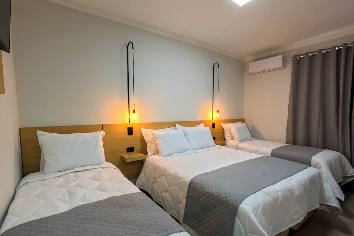 Une chambre d’hôtel avec deux lits, chacun doté d’une tête de lit, de tables de chevet et de lampes fixées au mur.