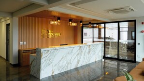 A hotel reception area with a marble counter, wooden paneling, and pendant lighting. - Terraço Plaza Hotel (Jaboticabal)