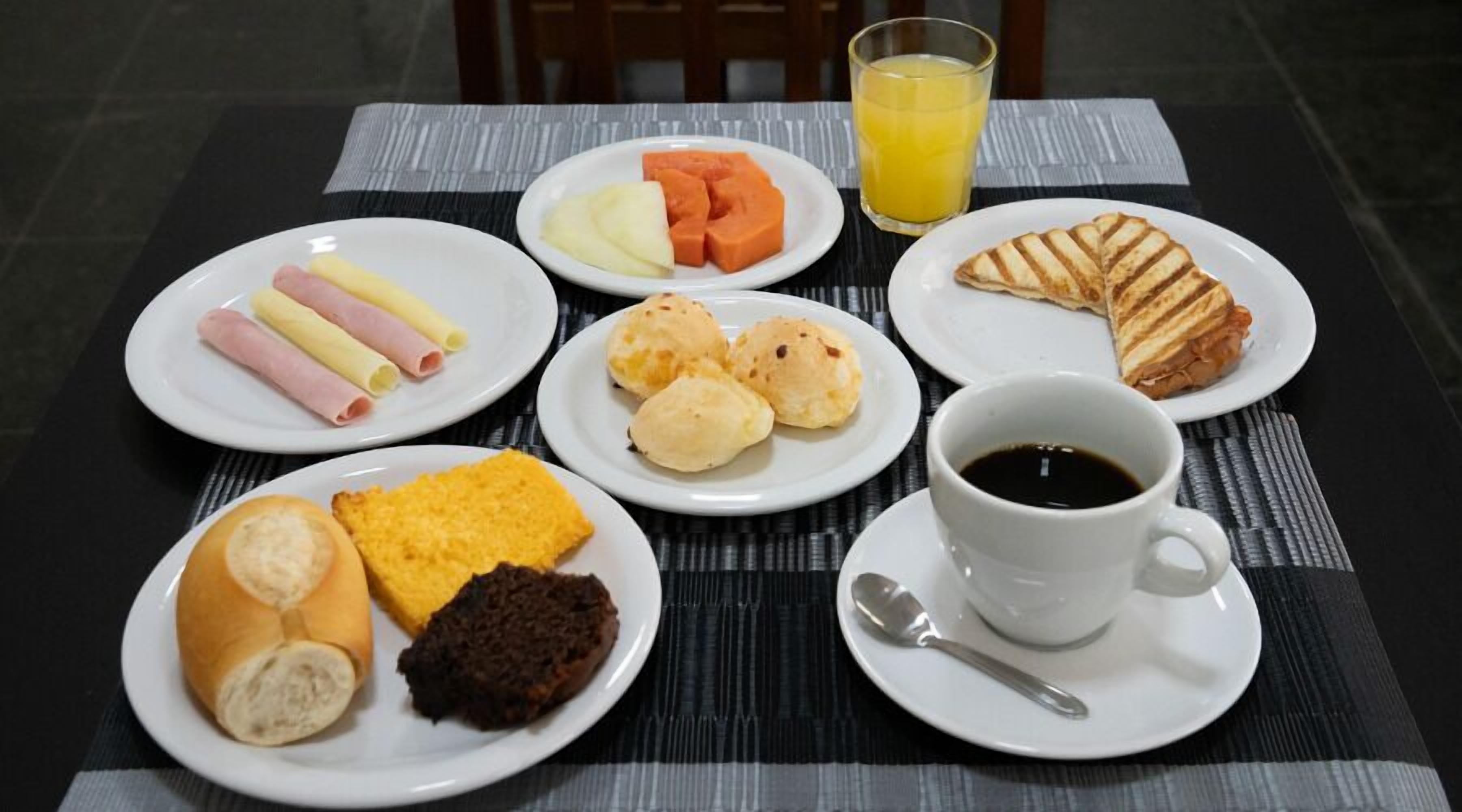 A breakfast setting with plates of food, a glass of orange juice, and a cup of coffee.