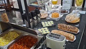 A buffet with various food items, a toaster, and condiments. - Terraço Plaza Hotel (Jaboticabal)