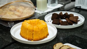 A table with a yellow dessert, a plate of brownies, and a basket of round pastries. - Terraço Plaza Hotel (Jaboticabal)