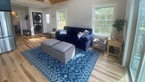 Un vaste espace de vie agrémenté d’un tapis à motifs bleus, d’un canapé bleu foncé et d’un plafond en bois.