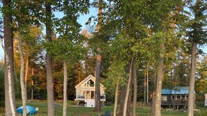 Une jetée en bois menant à une maison entourée d’arbres.