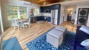 Une cuisine spacieuse équipée d’appareils modernes, un coin repas avec une table et des chaises en bois, et une grande fenêtre donnant sur l’extérieur.
