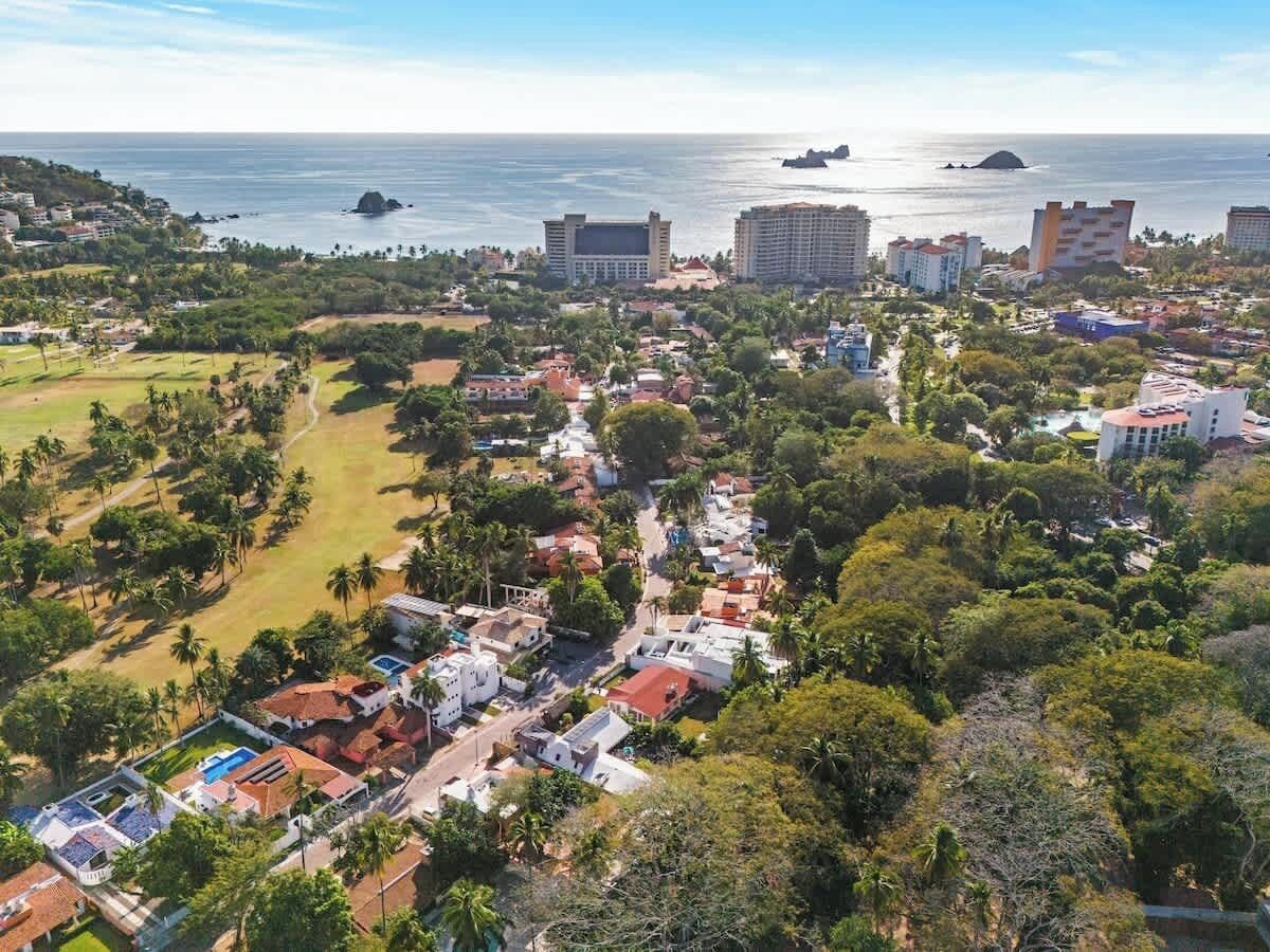 An aerial view of a coastal town with buildings, roads, and greenery.