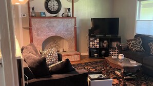 Een woonkamer met een open haard, een bank, een salontafel en een televisie.
