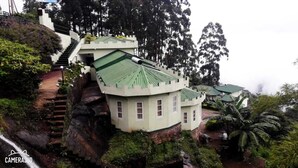 Un bâtiment doté d’un toit végétalisé, situé sur une colline, avec un escalier menant à son entrée.