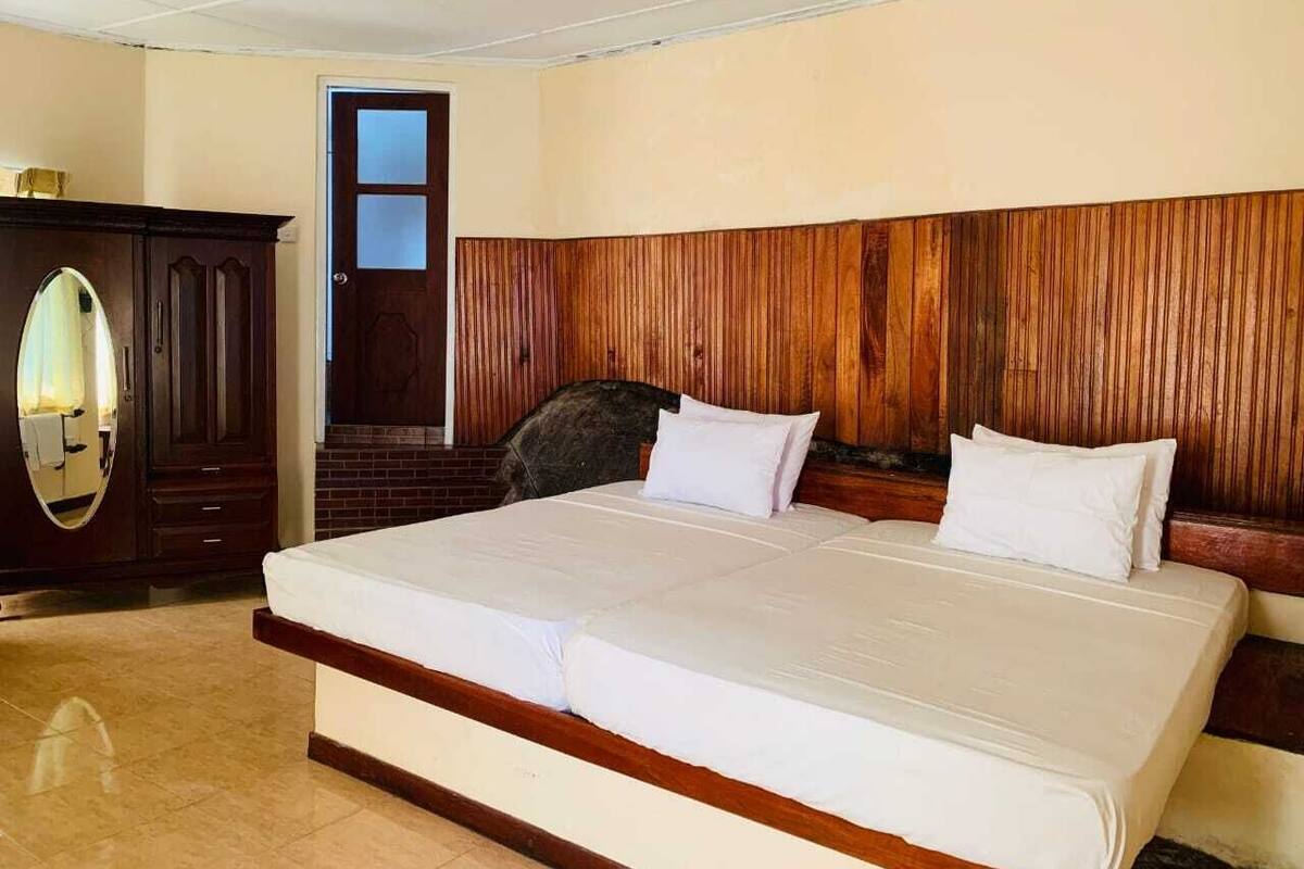 Una cama grande con cabecera de madera, un armario de madera oscura y un ventanal pequeño.