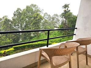 Un balcón con sillas de mimbre y vistas a un paisaje verde exuberante.